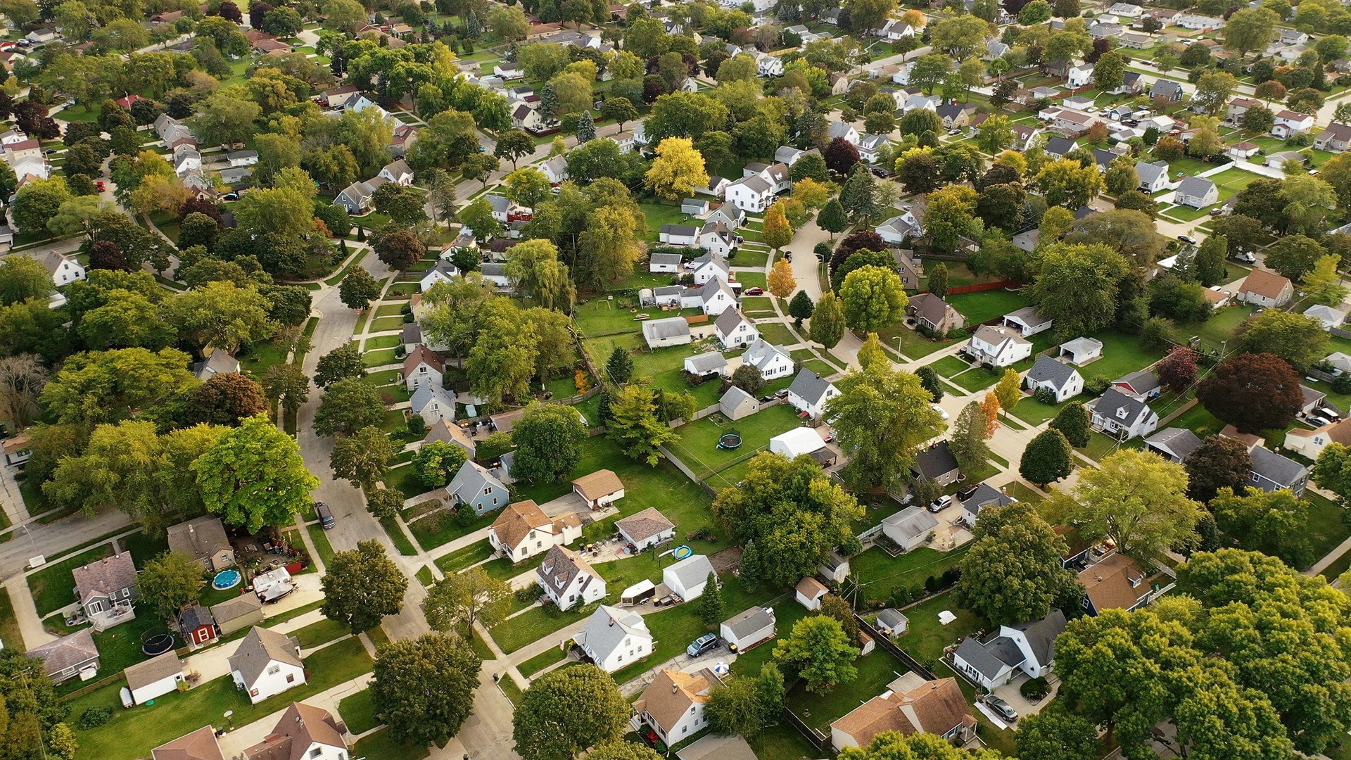 Aerial drone view of American suburban neighborhood at daytime. Establishing shot of America's  suburb. Residential single family houses pattern